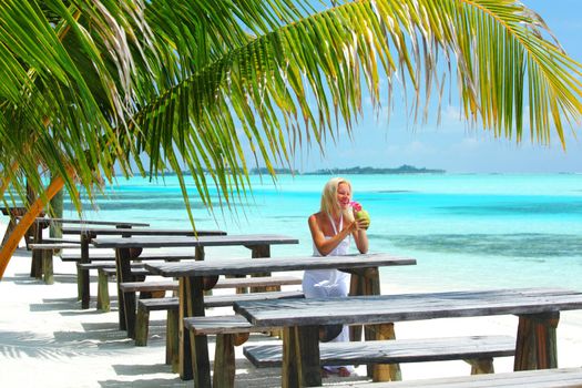 woman sitting in a tropical cafe on the background of a  palm trees and sky and sea