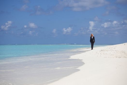 business woman with briefcase walking on the desolate ocean coast