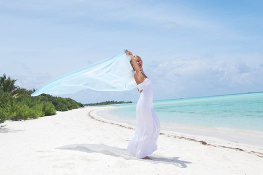 woman with a white fabric in his hands on the beach