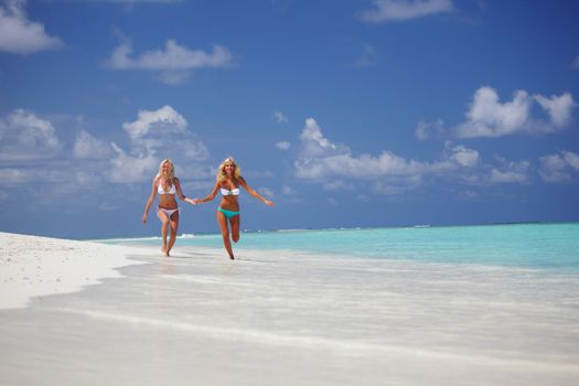 Two girls run along the ocean coast