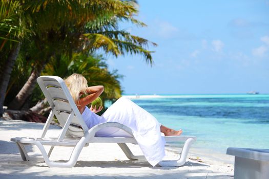 tropical woman on lounge with a coconut cocktail