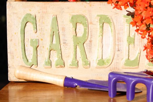 Ornate garden sign with orange flowers and purple garden tools