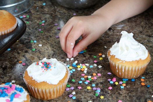 Little fingers picking up star cake decorations