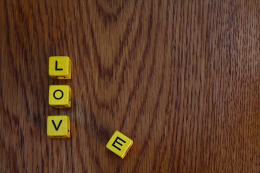 Yellow blocks on wooden surface spelling Love