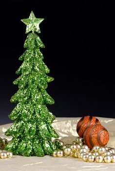 Christmas tree decorations made out of green sequins on golden cloth and dark background.