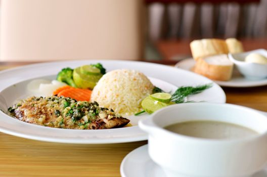 roasted fish served with fried rice and mushroom soup and bread