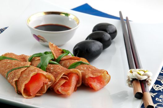 red raw fish wrapped in crepes and tied with green onions, olives and dressing