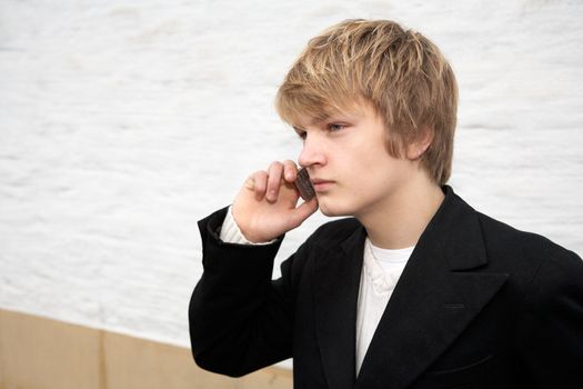 Teenage boy using mobile phone by building wall