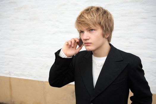 Teenage boy using mobile phone outdoor by white building wall