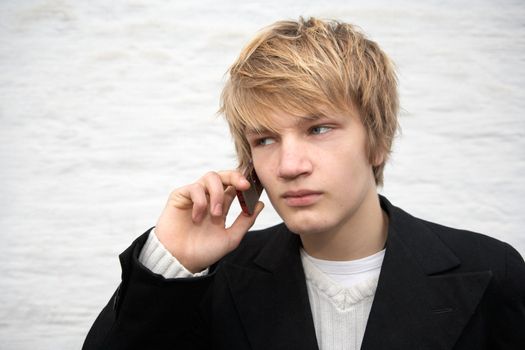 Teenage boy with mobile phone, white building wall in background