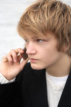 Teenage boy with mobile phone by white wall, close-up