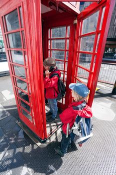 Boy talking in traditional red London pay phone box