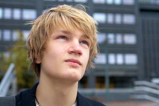 Portrait of hopeful teenage boy outdoor in city, contemplating