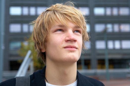 Portrait of confident teenage boy outdoor in city, looking up