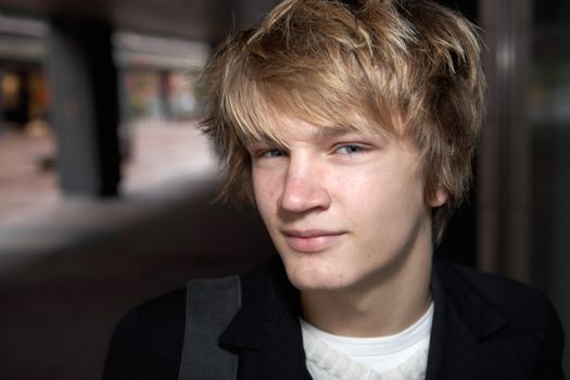 Portrait of teenage boy smiling in city street, looking at camera