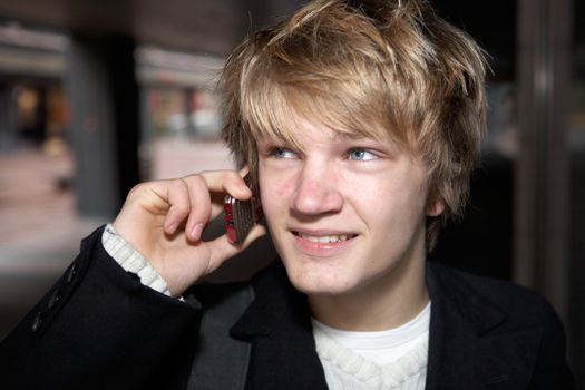 Smiling teenage boy talking on mobile phone in city street