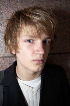 Teenage boy against building wall, looking at camera