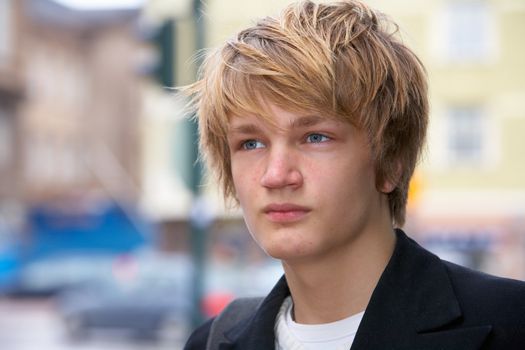 Portrait of teenage boy in street, looking away