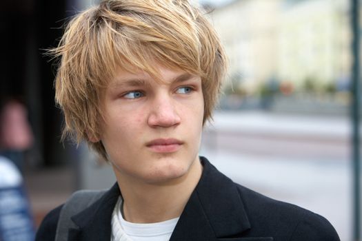 Portrait of contemplating teenage boy in street, looking away