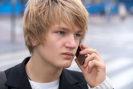 Teenage boy using mobile phone in street, close-up