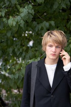 Teenage boy using mobile phone in city park, copy space