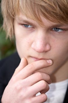 Teenage boy contemplating in city park, close-up