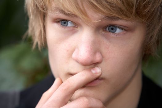 Teenage boy contemplating in city park, close-up