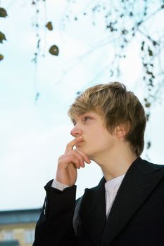 Teenage boy contemplating in city park, low angle view