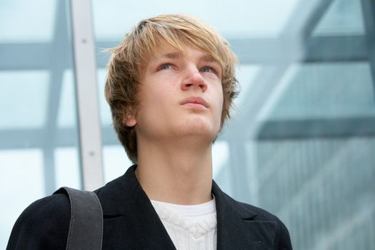 Teenage boy contemplating in urban environment, looking up