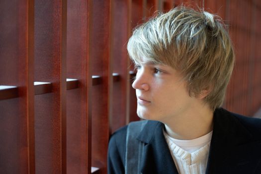 Interior shot of teenage boy by wooden panel shades