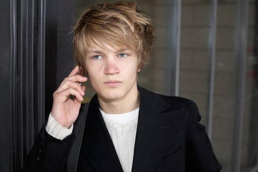 Teenage boy on mobile phone outside modern building