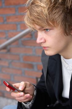 Teenage boy holding mobile phone, looking away