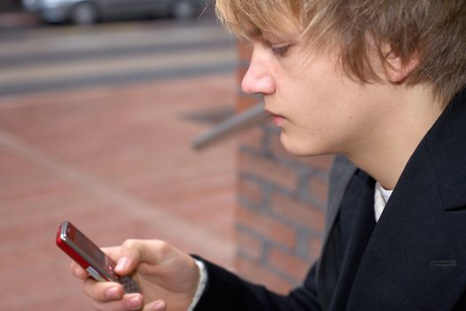 Teenage boy text messaging with mobile phone, close-up