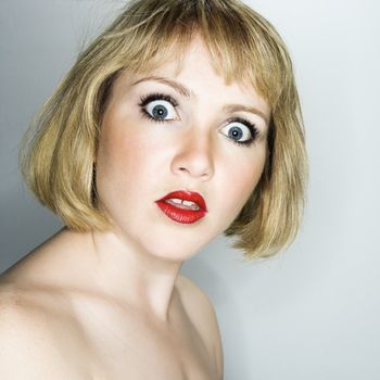 Portrait of young blonde caucasian woman who is looking at the viewer with confused expression.