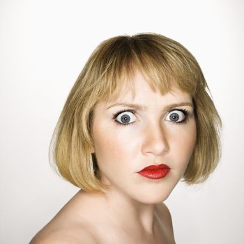 Portrait of young blonde caucasian woman who is looking at the viewer with confused expression.