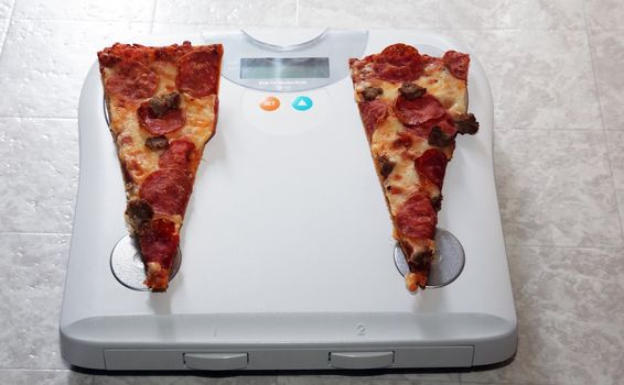 Two pieces of pizza sit on a scale representing feet.  
