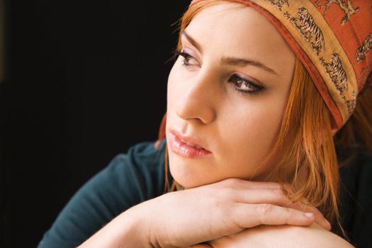 Young redheaded woman wearing cap looking off to side.