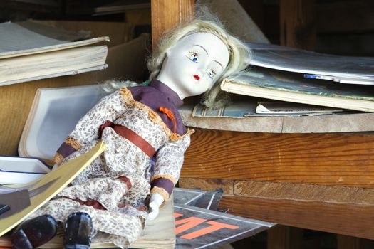 Old baby doll sitting on shelf.