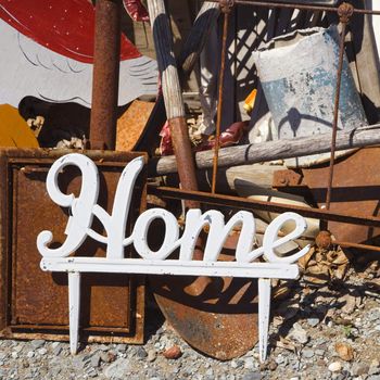 Metal figure with word "Home" leaning against junk.