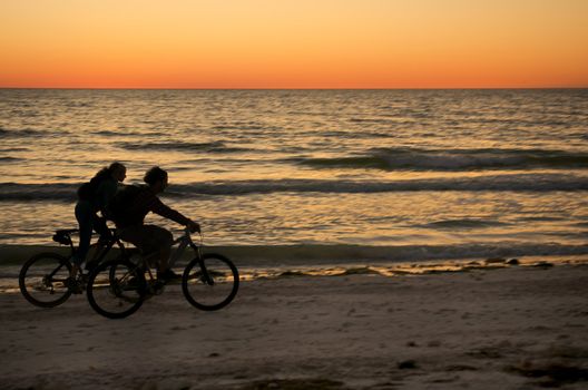 Couple ryding bycicle at sunset in Honeymoon Island, Florida.