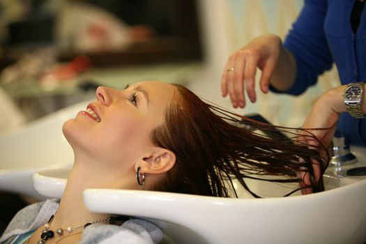 Barber makes a hair-dress to the young brunette