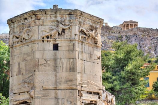 Ancient Tower of the Winds (Horologion or Aerides) in Athens, Greece. It served as a compass, sundial, wetaher vane and water clock. Each face of the frieze is adorned with a relief of one of the god winds. Akropolis in the background. HDR.