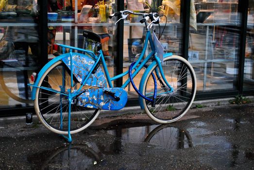 a blue bicycle and a portret of the lady in the glass-case