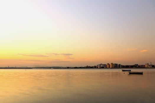 The city and the river with two small boats at sunset.