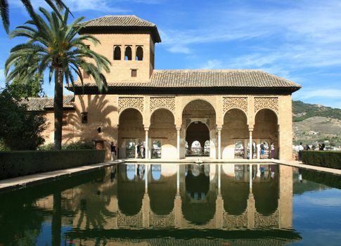 Torre de las Damas and its reflection in a pool in the Alhambra of Granada, Spain.