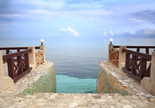 Steps leading into the Caribbean Sea, merging with the sky, at dusk.