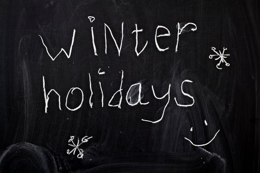Inscription "winter holidays", written by a child's hand on the chalk board