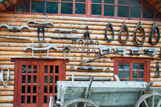 Horseshoes and other supplies for the horses on display on the wall of wooden houses