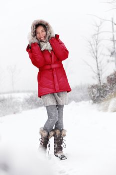 Winter snow woman having fun outside. Cute happy smiling young mixed race Asian Caucasian woman playful in the snow.