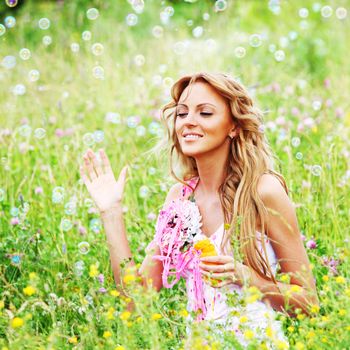  Blonde starts soap bubbles in a green field